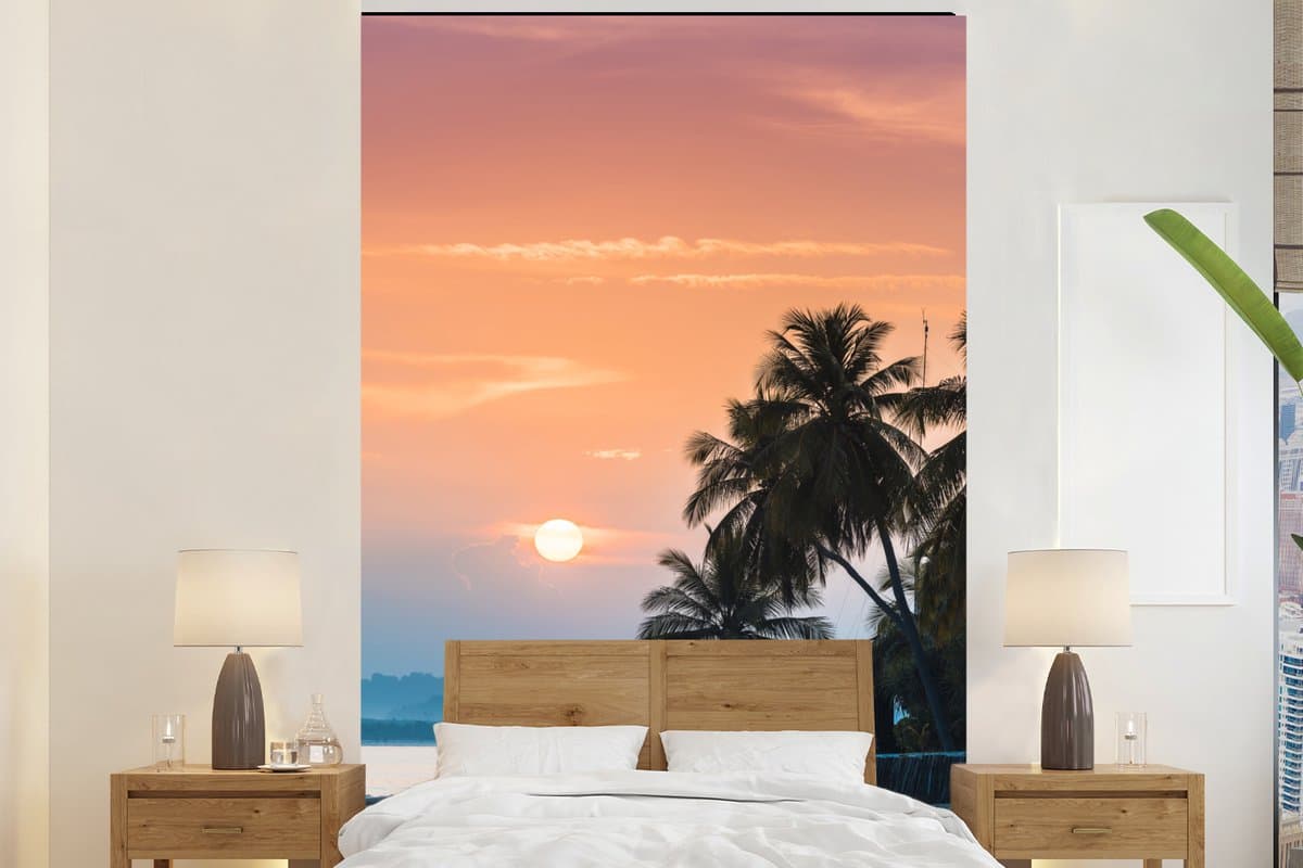 Behang - Fotobehang Zonsondergang op een eiland met de silhouetten van palmbomen - Breedte 145 cm x hoogte 220 cm